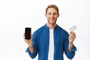 Smiling happy man showing mobile phone blank screen bank credit card recommending smartphone application online shopping app standing white background