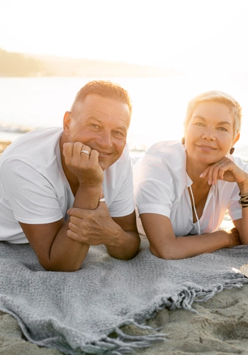 Full shot couple laying towel beach