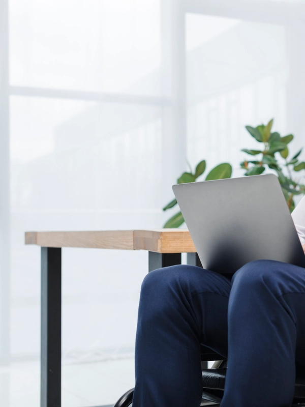 Happy disabled young businessman sitting wheelchair using laptop office