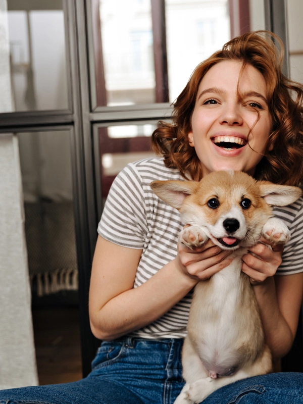 Positive woman sits floor living room with smile plays with her beloved dog