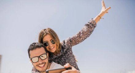 Man taking photograph her girlfriend enjoying piggyback ride his back