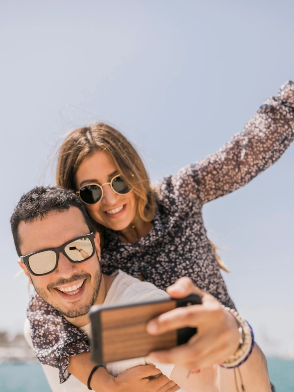 Man taking photograph her girlfriend enjoying piggyback ride his back