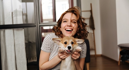 Positive woman sits floor living room with smile plays with her beloved dog