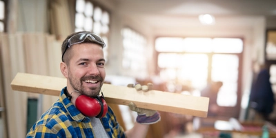 Portrait professional carpenter holding wood plank material his shoulder smiling