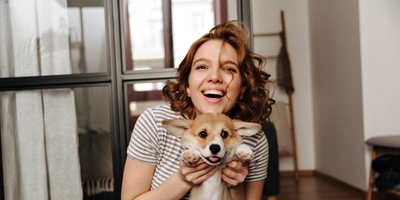Positive woman sits floor living room with smile plays with her beloved dog
