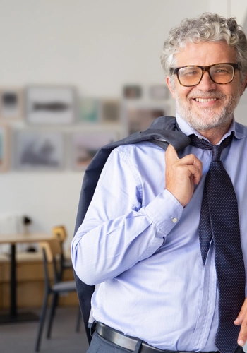 Happy relaxed mature business man standing office cafe leaning counter holding jacket shoulder smiling camera