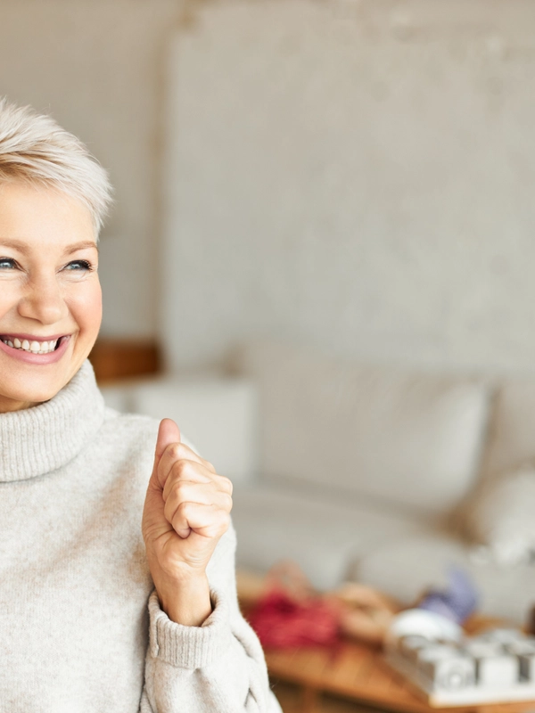 Indoor shot fashionable overjoyed mature female turtleneck sweater enjoying positive news having ecstatic facial expression laughing clenching fists success achievements concept