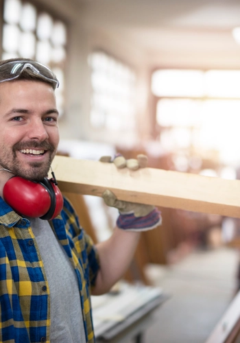 Portrait professional carpenter holding wood plank material his shoulder smiling