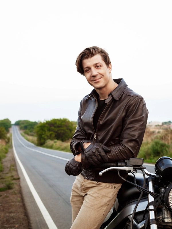 Young handsome man posing near his motorbike countryside road