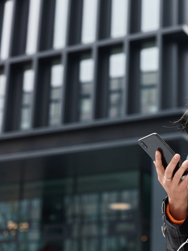 Photo charming dreamy woman holds modern cellular listens music walk outdoor metropolis