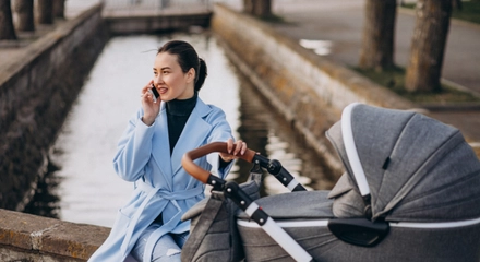 Young mother sitting with baby carriage park