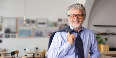 Happy relaxed mature business man standing office cafe leaning counter holding jacket shoulder smiling camera
